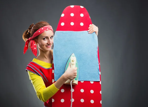 Улыбающаяся домохозяйка с гладильной доской — стоковое фото