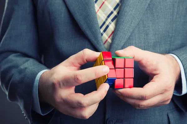 Empresário segurando cubo de rubik — Fotografia de Stock