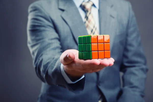 Empresário segurando cubo de rubik — Fotografia de Stock