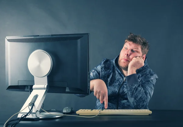 Homme assis au bureau regardant sur l'écran d'ordinateur — Photo