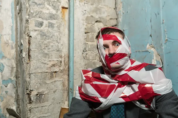 Man with stripped duct tape over body in old house — Stock Photo, Image