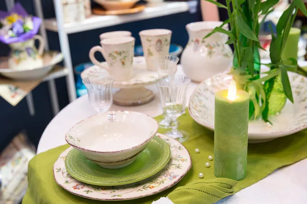 Groene tafel geserveerd met bedjes en platen — Stockfoto