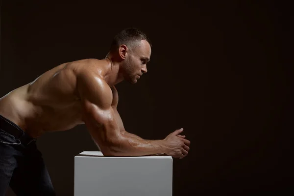 Hombre atleta muscular posa en el cubo en el estudio —  Fotos de Stock