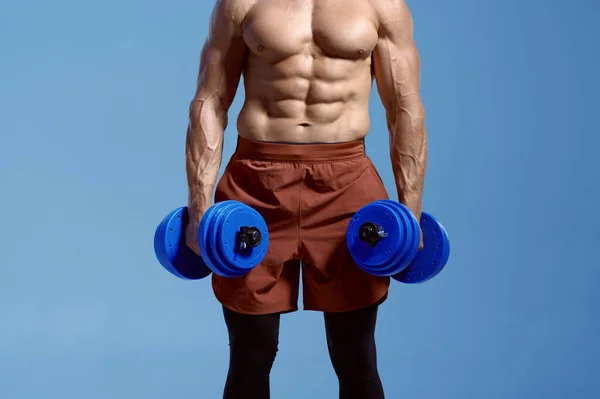 Male athlete with muscular body holds dumbbells — Stock Photo, Image