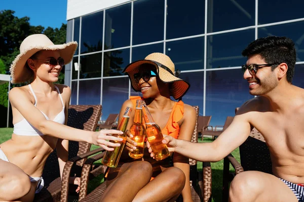 Freunde klirren mit Bierflaschen am Pool — Stockfoto