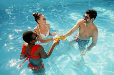 Arkadaşlar havuzda içki içer, manzarası güzeldir.