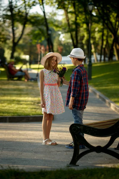 Мальчик с цветами ждет девушку на скамейке запасных — стоковое фото