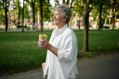 Komik büyükanne yaz parkında kahve içer.
