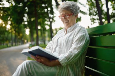 Dranny, yaz parkında bankta kitap okuyor.