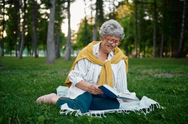 Bardaklı tuvalet çimenlerin üzerinde kitap okuyor.