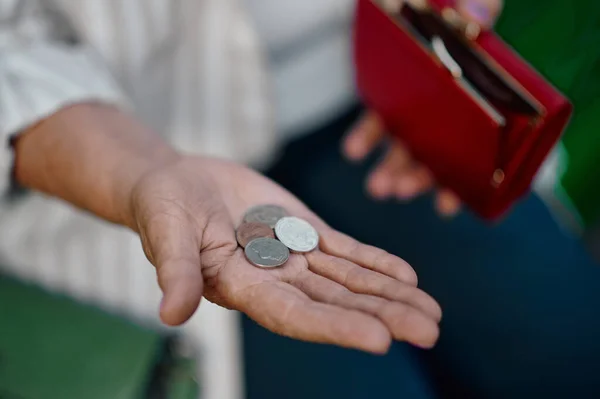 Granny shows a trifle in her wallet in summer park — Stock Photo, Image