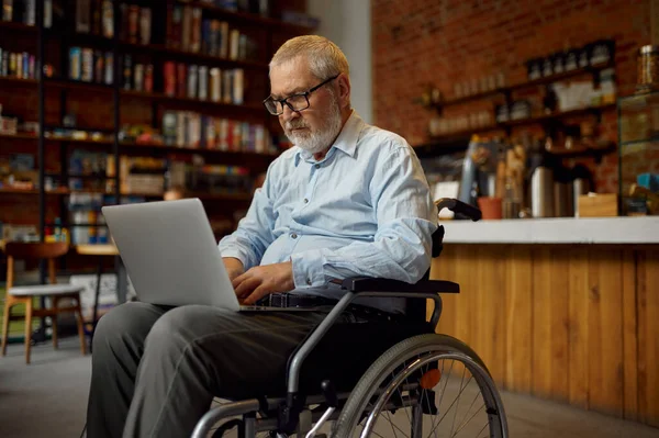Felnőtt fogyatékos férfi tolószékben laptoppal — Stock Fotó