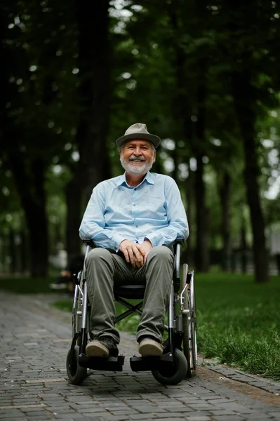 A kerekesszékben ülő, fogyatékkal élő felnőtt férfi papírlapot tart — Stock Fotó