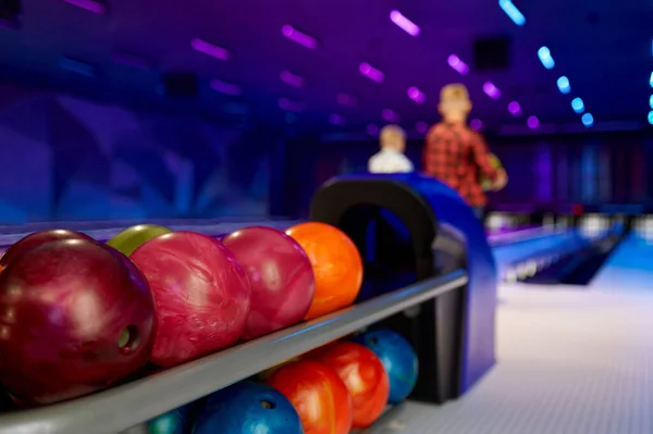 Bowling-Bälle, zwei Jungen auf der Bahn im Hintergrund — Stockfoto