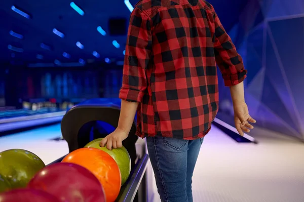 Rapaz leva uma bola na pista no bowling beco — Fotografia de Stock