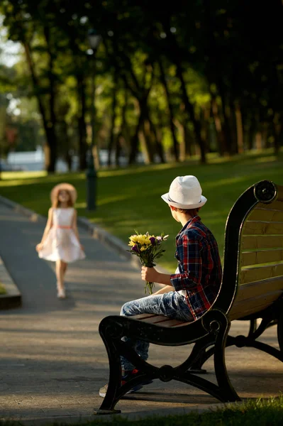 Boy with flowers waiting for a girl on the bench — Stock Photo, Image