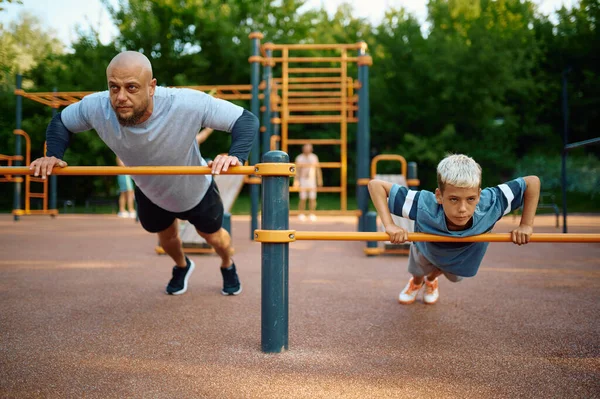 Isä ja lapsi tekevät liikuntaa, urheilukoulutusta — kuvapankkivalokuva