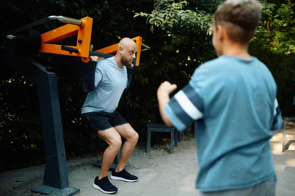 Pai e menino na máquina de exercícios, treinamento esportivo — Fotografia de Stock