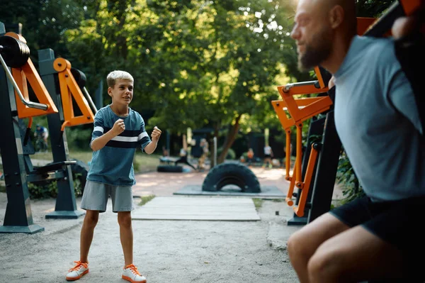Πατέρας και αγόρι σε μηχάνημα γυμναστικής, αθλητική εκπαίδευση — Φωτογραφία Αρχείου