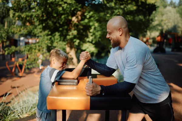 Père et fils, exercice de bras de fer, aire de jeux — Photo