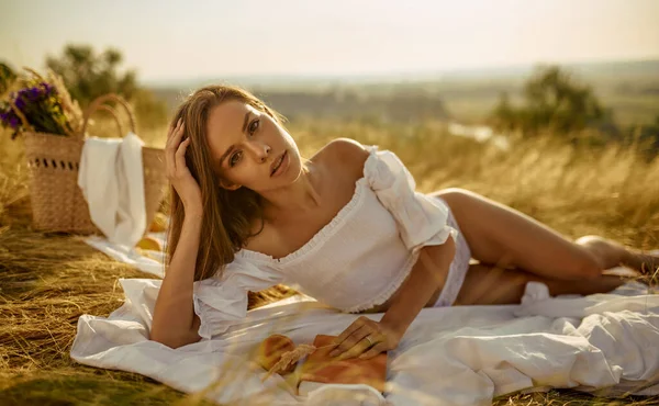 Mujer sexy en lencería acostada con libro en el campo — Foto de Stock