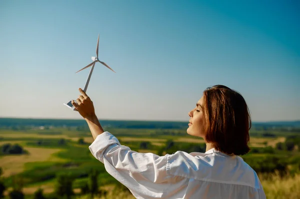Kobieta trzyma model turbiny wiatrowej w terenie — Zdjęcie stockowe