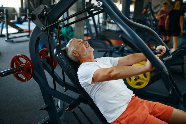 Velho alegre na máquina de exercícios no ginásio — Fotografia de Stock