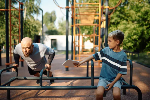 Papa en zoon op trainingsmachine, sport training — Stockfoto