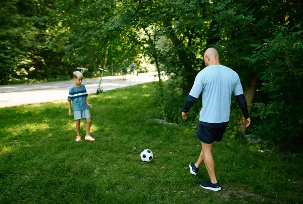 Padre e hijo juegan al fútbol en la hierba al aire libre — Foto de Stock