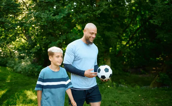 Πατέρας και γιος παίζουν ποδόσφαιρο την ηλιόλουστη μέρα. — Φωτογραφία Αρχείου