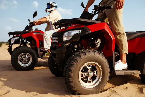 Men in helmets and glasses ride on atv in desert — Stock Photo, Image