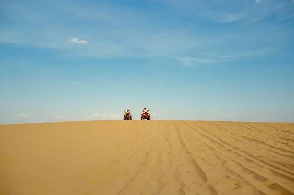 Двоє гонщиків, які їдуть на atv в пустелі, здалеку — стокове фото