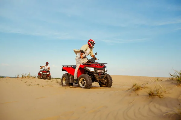 Kasklı bir adam çölde ATV 'ye biniyor. — Stok fotoğraf