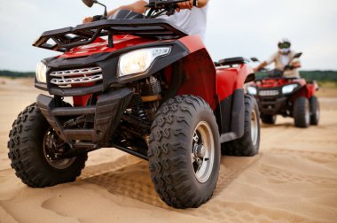 İki adam çölde ATV 'ye biniyor.