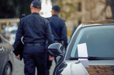 İki erkek polis memuru araba parkını kontrol ediyor.