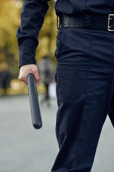 Male police officer in uniform holds baton — Stock Photo, Image