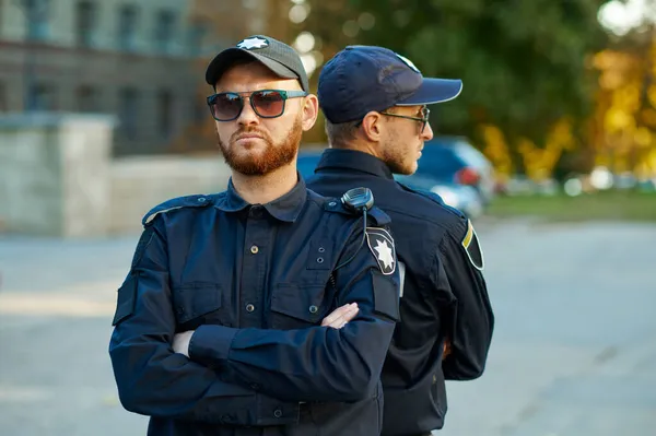 两名男警察背靠背地站着 — 图库照片