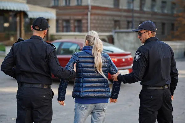 Deux policiers hommes arrêtent une jeune femme — Photo