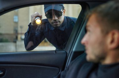 Polis devriyesi erkek sürücünün arabasını kontrol ediyor.