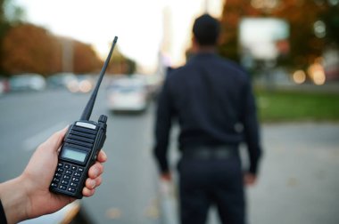 Polis memuru elinde bir telsiz tutuyor.