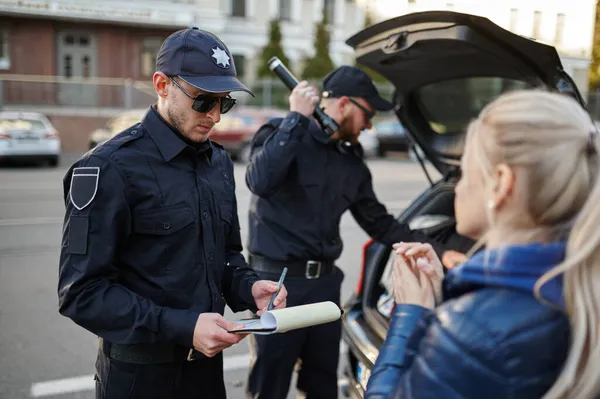 Полицейский патруль останавливает женщину и проверяет машину — стоковое фото