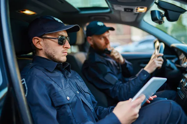 Zwei männliche Polizisten in Uniform posieren im Auto — Stockfoto