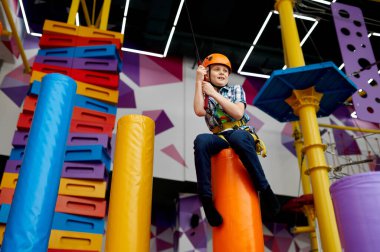 İpte küçük bir çocuk, kasklı genç bir dağcı.