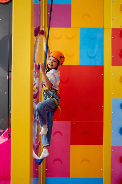 Mała dziewczynka w kasku pozuje na ściance wspinaczkowej — Zdjęcie stockowe