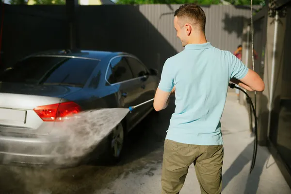 Muž drží vysokotlaké vodní pistole, mytí aut — Stock fotografie