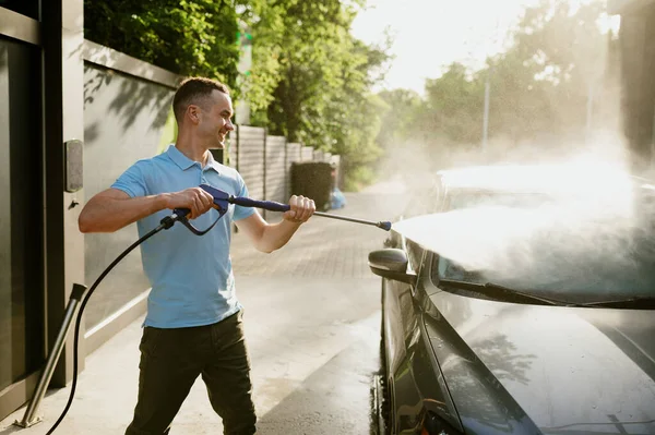 El hombre tiene pistola de agua de alta presión, lavado automático — Foto de Stock