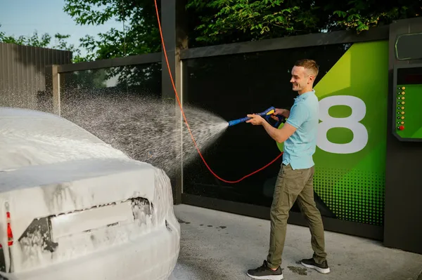 Hombre con pistola de agua con espuma, lavado de autos a mano — Foto de Stock