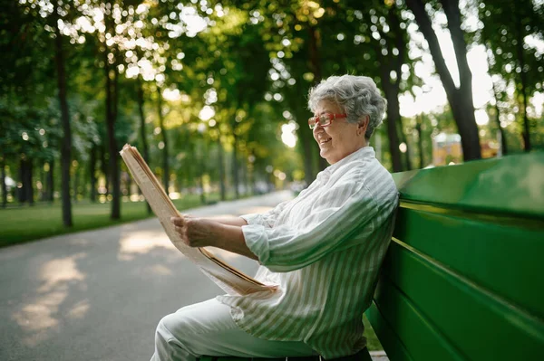 ベンチで新聞を読んでいる年配の女性 — ストック写真