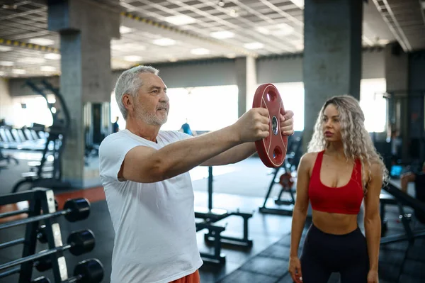 Viejo haciendo ejercicio con barra, entrenador femenino — Foto de Stock