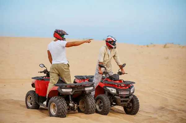 Два человека в шлемах, атв на песках пустыни — стоковое фото